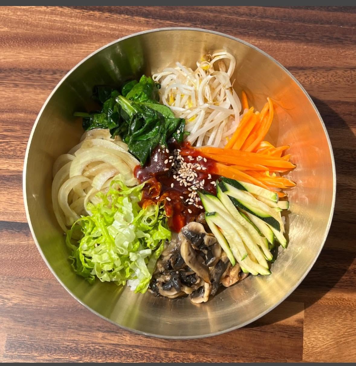 Bibimbap bowl with spinach, bean sprouts, carrot, zucchini, mushrooms and chilli paste