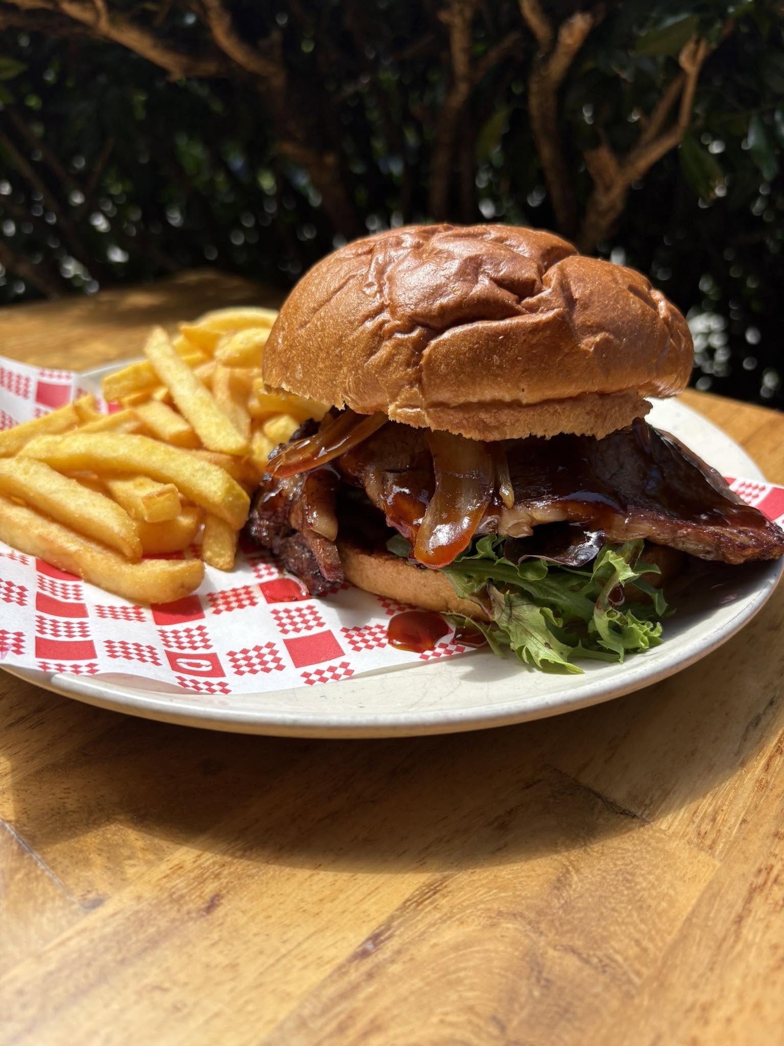 Burger with glazed meat and caramelised onion served with chips