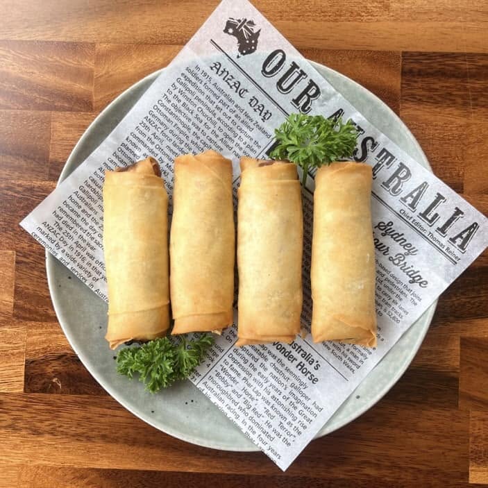 Four golden fried rolls on a plate garnished with parsley